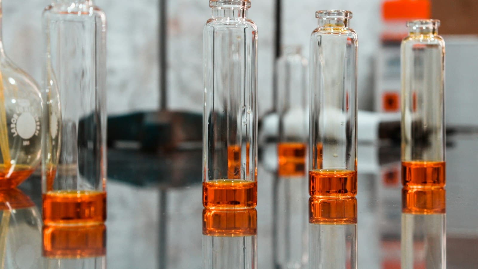 چند ویال شیشهای با روغن عطر کهربایی، روی سطح روشن